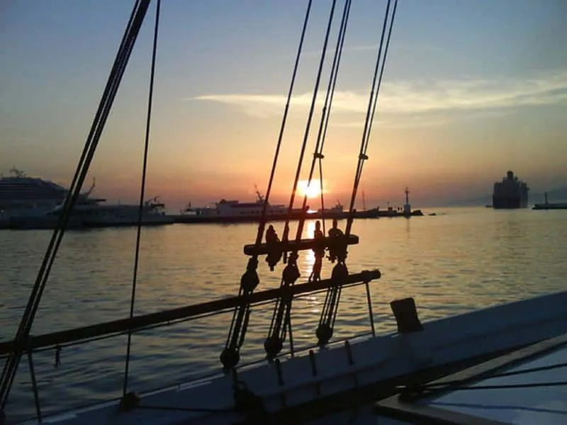 Sailing boat at sunset passing Little Venice windmills on a Mykonos island nightlife and sunset cruise